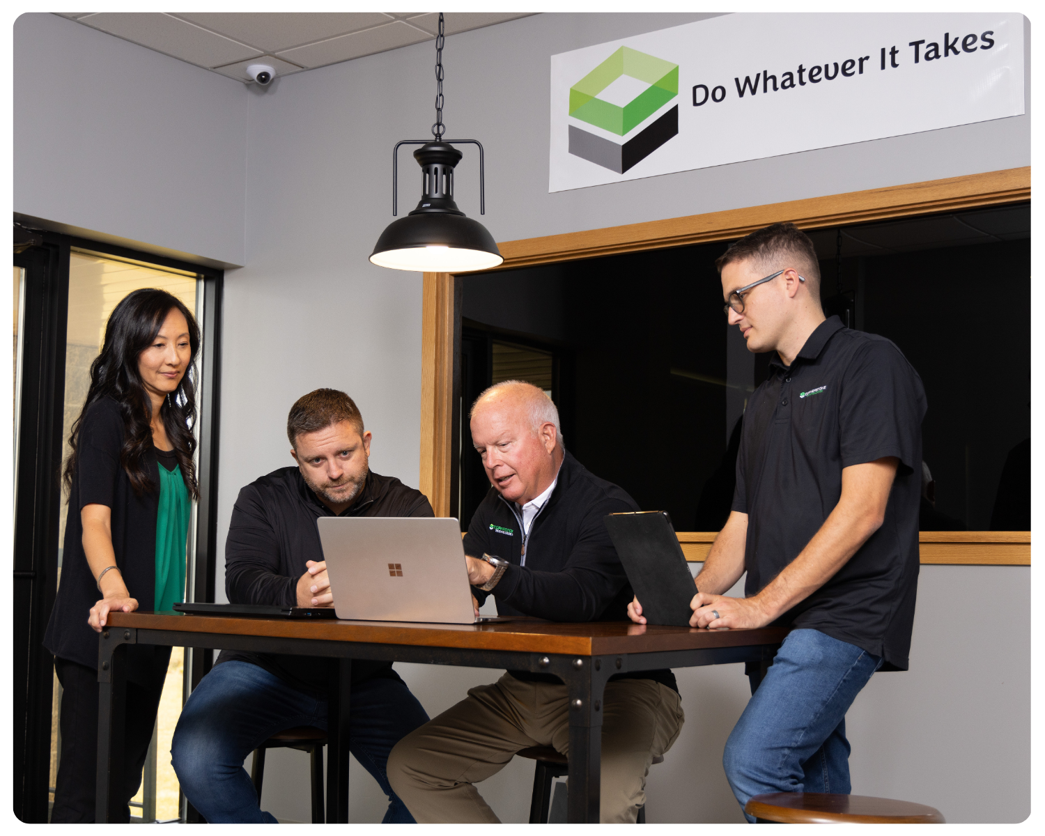 A photo of four Cornerstone Technologies employees at a laptop