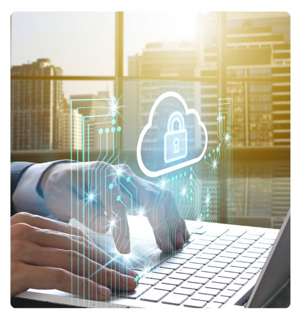 A person typing on a computer in a tall city building wth a digital cloud and padlock floating over the keyboard.