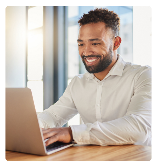 A happy person on a laptop sitting at a table.