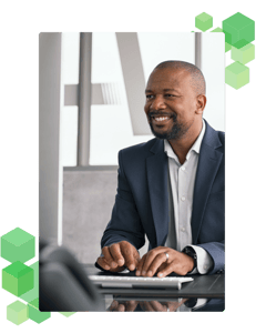 A smiling person working at their desk and typing on a keyboard.